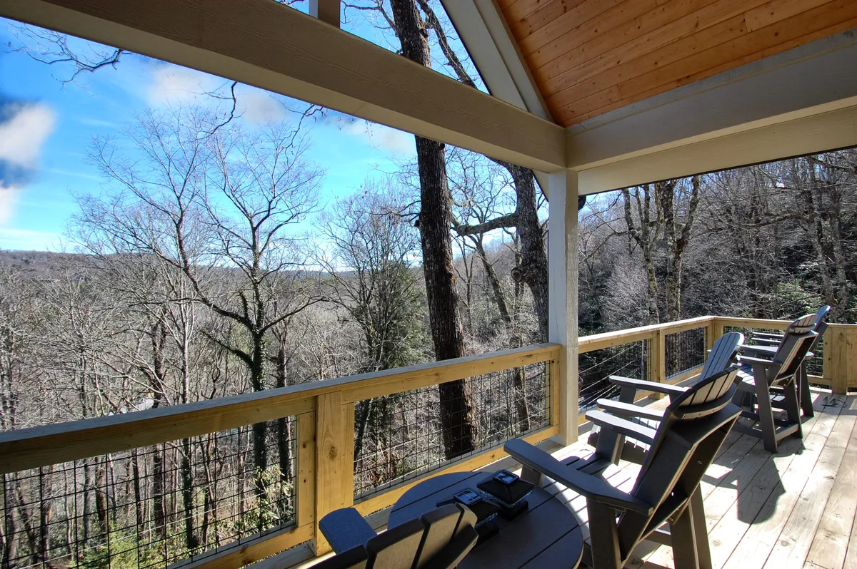 This inviting exterior scene shows a wooden deck with rocking chairs overlooking a distant tree line. The relaxed, open setting captures the transition between the home environment and the broader outdoors, suggesting a pause along the journey or a place to unwind after returning from downtown.